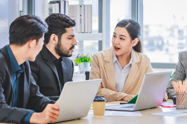Group of millennial Asian Indian multinational multicultural male and female businessman businesswoman teamwork in formal suit sitting smiling brainstorming meeting together in office conference room.