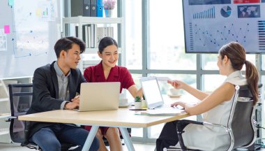 Milenyum Asyalı çok kültürlü erkek ve kadın iş kadını takım çalışması resmi takım elbise içinde oturmuş, beyin fırtınası yaparken ofis konferansı odasında birlikte gülüyorlar..