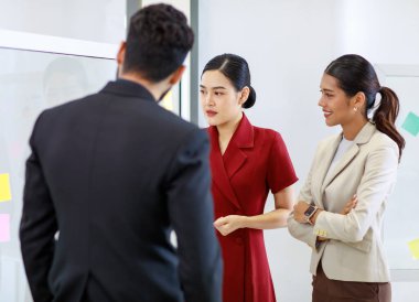Asyalı genç, güzel, profesyonel, başarılı iş kadını gülümseyip grafik çizelgesini sunuyor. Veri belgelerini cam tahtada kadın ve erkek meslektaşlarına sunuyor..