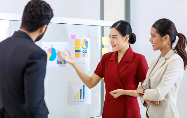 アジアの若い美しいプロの成功したビジネス女性が笑顔の手を握って立ってグラフ報告書のデータを示すグラフを提示男性と女性の同僚にガラス板上の書類 — ストック写真