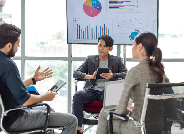 Millennial Indian Asian professional successful male female businessman businesswoman group in formal suit sitting together discussing brainstorming sharing business solution ideas in meeting room.