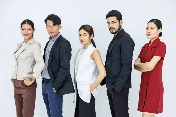 Studio shot Asian Indian male female professional successful businessmen and businesswomen group in formal suit standing in line posing crossed arms holding hands in pants pocket on white background.