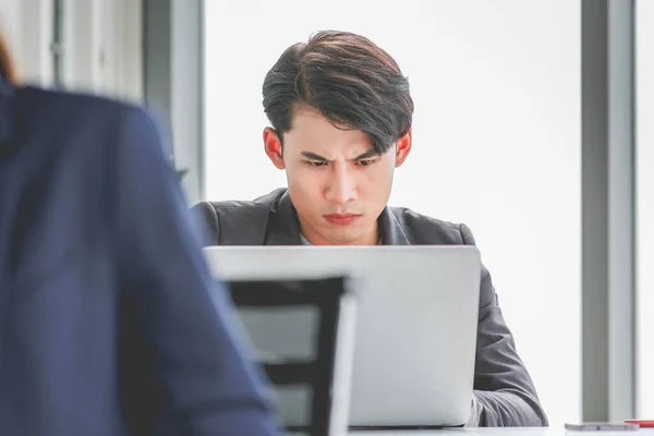 Closeup shot of millennial Asian stressed depressed upset unhappy tired frowning face male businessman employee has problem work hard overload overtime with laptop notebook computer in company office.