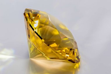 Kendi kendini kesen bir Zirkonya küpünün detaylı fotoğrafı. Orta boy şampanya rengi ve yuvarlak parlak Split ana kesimi, beyaz akrilik cam bir yüzeye yerleştirilmiş ve taç sağ üst tarafa dönük.