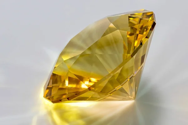 Detail photo (focus stacking) of a self-cut Cubic Zirconia with Champagne medium color and Round Brilliant Split Mains cut, placed on a white acrylic glass surface with the crown facing top left
