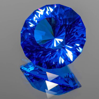 Detail photo (focus stacking) of a self-cut synthetic Spinel with Zirconiumblue nr120 color and In-line Crown cut, placed on a mirror with the crown facing top left