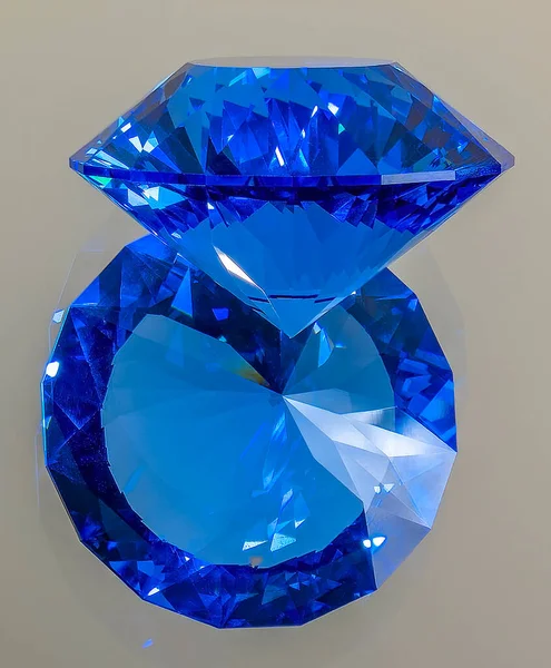 Detail photo (focus stacking) of a self-cut synthetic Spinel with Zirconiumblue nr120 color and In-line Crown cut, placed on a mirror with view of the girdle and the crown facing up