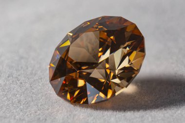 Detail photo (focus stacking) of a self-cut Cubic Zirconia with Champagne medium color and Standard Round Brilliant cut, placed on white velvet with the crown facing top left