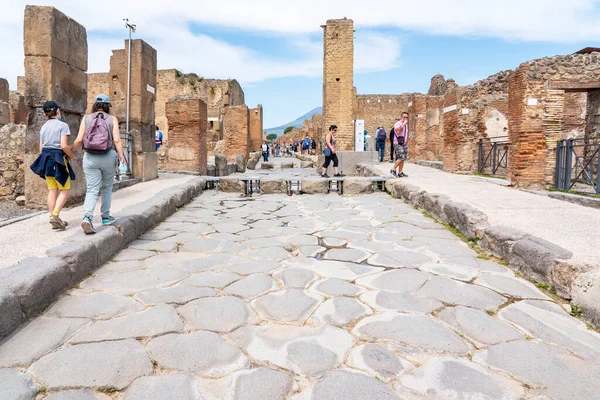 One of the main streets with a pedestrian crossing with the openings for the wheels of the carts and carriages in the city of Pompeii, Italy
