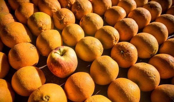 Apple onder sinaasappelen — Stockfoto