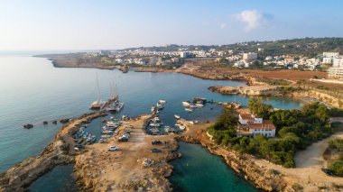Protaras, Paralimni, Famagusta, Kıbrıs 'taki Green Bay' in havadan kuş bakışı görüntüsü. Ünlü turist eğlencesi dalış yeri kayıklar, güneşlikler, restoranlar, su sporları, yaz tatillerinde denizde yüzen insanlar, yukarıdan.