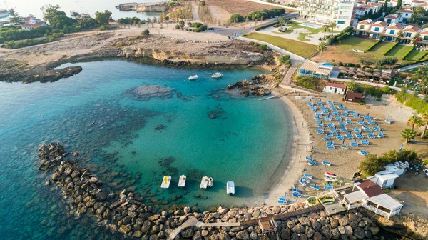 Aerial bird\'s eye view of Green bay in Protaras, Paralimni, Famagusta, Cyprus. The famous tourist attraction diving location rocky beach with boats, sunbeds, restaurants, water sports, people swimming in sea on summer holidays, from above.