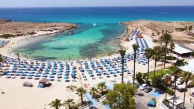 Aerial bird's eye footage view of Vathia Gonia beach, Ayia Napa, Famagusta, Cyprus. The landmark tourist attraction rocky bay with golden sand, sunbeds, sea restaurants in Agia Napa on summer holidays, from above.