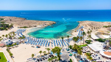 Vathia Gonia plajı, Ayia Napa, Famagusta, Kıbrıs 'ın havadan kuş bakışı görüntüsü. Gündoğumunda, Agia Napa 'da yaz tatillerinde altın kum, güneşlik, deniz restoranları ve deniz restoranlarıyla turistik bölge kayalık körfezi..