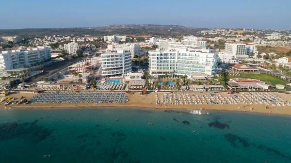 Aerial bird\'s eye view of Sunrise beach at Fig tree in Protaras, Paralimni, Famagusta, Cyprus. The famous tourist attraction family bay with golden sand, boats, sunbeds, restaurants, water sports, people swimming in sea on summer holidays, from above
