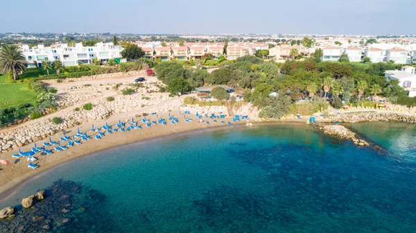 Aerial bird's eye view of Sirena beach in Protaras, Paralimni, Famagusta, Cyprus. The famous Sirina bay tourist attraction with sunbeds, golden sand, restaurant, people swimming in sea on summer holidays from above.