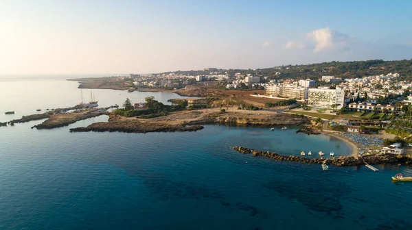 Aerial bird\'s eye view of Green bay in Protaras, Paralimni, Famagusta, Cyprus. The famous tourist attraction diving location rocky beach with boats, sunbeds, restaurants, water sports, people swimming in sea on summer holidays, from above.