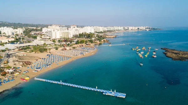 Aerial bird\'s eye view of Fig tree bay in Protaras, Paralimni, Famagusta, Cyprus. The famous tourist attraction family golden sandy beach with boats, sunbeds, restaurants, water sports, people swimming in sea on summer holidays, from above.