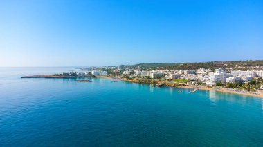 Protaras, Paralimni, Famagusta, Kıbrıs 'taki Fig Tree' deki Sunrise plajının havadan kuş bakışı görüntüsü. Altın kumu, tekneleri, güneşliği, restoranları, su sporları, yaz tatillerinde denizde yüzen insanları olan ünlü turistik aile körfezi.