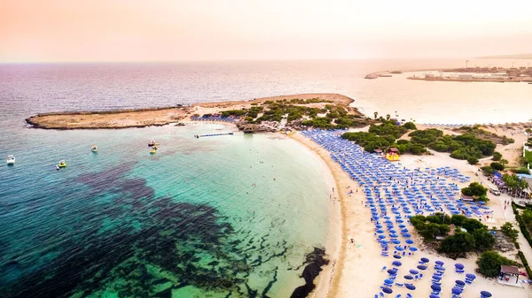 Ünlü Makronissos sahil şeridi Ayia Napa, Famagusta, Kıbrıs 'ın havadan kuş bakışı manzarası. Günbatımında Agia Napa 'da altın kum, güneşlik, deniz restoranları ve yaz tatilleri ile turistik mekan Makronisos Körfezi..