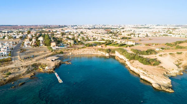 Aerial bird\'s eye view of Kapparis (fireman\'s) beach in Protaras, Paralimni, Famagusta, Cyprus. The famous tourist attraction golden sandy Kaparis bay with boats, sunbeds, restaurants, water sports, people swimming in sea on summer holidays, from abo