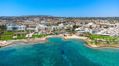 Protaras, Paralimni, Famagusta, Kıbrıs 'taki Pernera plajının kuş bakışı görüntüsü. Güneş yatakları, su sporları, oteller, restoranlar, yaz tatillerinde denizde yüzen insanlar....