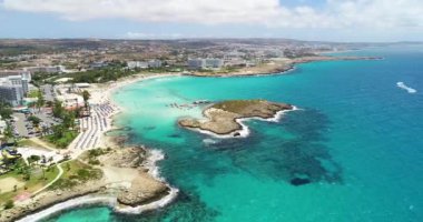 Aerial footage view of turquoise transparent crystal clean water of Nissi beach, Ayia Napa, Famagusta, Cyprus from above on a windy day. Moving away towards