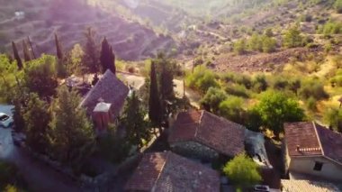 Geleneksel terk edilmiş ortaçağ kırsal köyü Phicardou (Fikardou), Lefkoşe, Kıbrıs Rum Kesimi 'nin hava gün batımı drone görüntüleri. Kilise ve terk edilmiş seramik seramik seramik çatı evleri yukarıdan dağlara