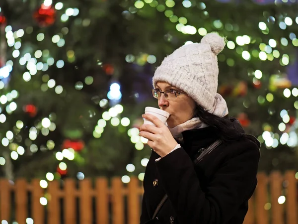 Genç Bir Kadın Noel Ağacının Önünde Sıcak Bir Içki Içer — Stok fotoğraf