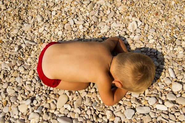 De kleine jongen viel in slaap op het strand. Rechtenvrije Stockfoto's