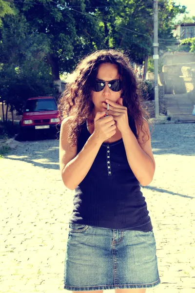 A girl lights a cigarette .. — Stock Photo, Image