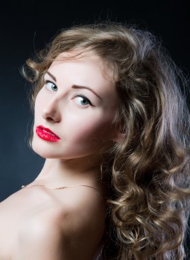 Portrait of a beautiful teen girl with long curly hairs and clean skin of the face - isolated on black