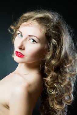 Portrait of a beautiful teen girl with long curly hairs and clean skin of the face - isolated on black