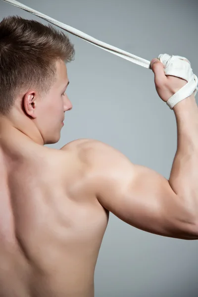 Vista trasera del joven flexionando sus músculos del bíceps sobre fondo blanco — Foto de Stock