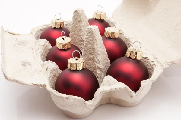 Caja de seis paquetes de huevos con bolas de Navidad rojas aisladas sobre fondo blanco — Foto de Stock