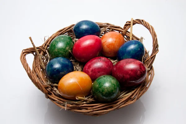 Huevos coloridos de Pascua en una cesta aislada sobre fondo blanco — Foto de Stock