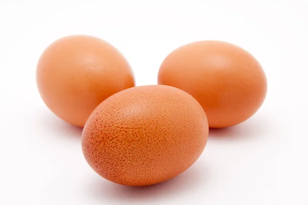 Три коричневых органических яйца на белом фоне — стоковое фото