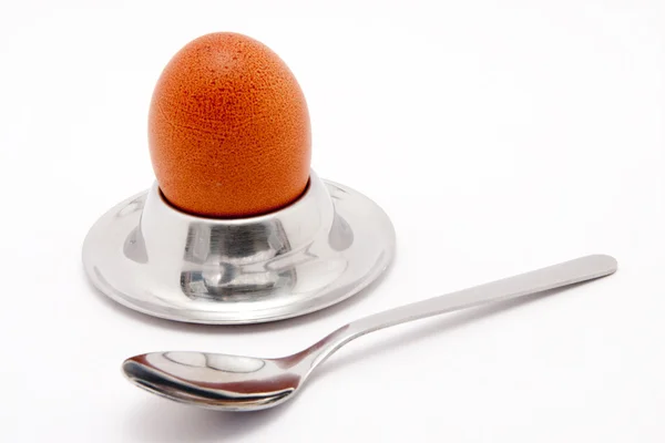 Яйцо с ложкой на белом фоне — стоковое фото