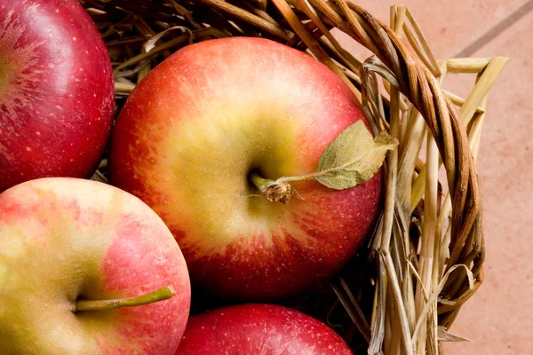 Fresh red apples in a basket with straw at daylight — Stock Photo, Image