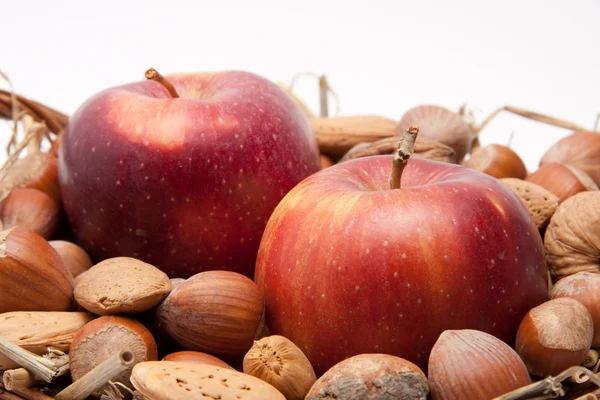 Červená jablka a ořechy v košíku izolovaných na bílém pozadí — Stock fotografie