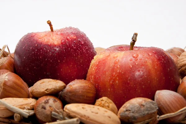 Červená jablka s kapky vody a ořechy izolovaných na bílém pozadí — Stock fotografie