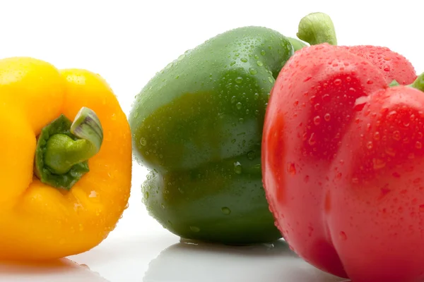 Beyaz arka plan üzerinde izole su damlaları ile taze sarı, turuncu ve yeşil biber