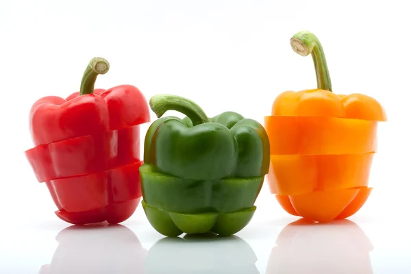 Segmenten van rood, groen en oranje peper geïsoleerd op witte achtergrond — Stockfoto