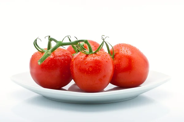 Juicy tomatoes with drops on a plate isolated against white background — Stock Photo, Image