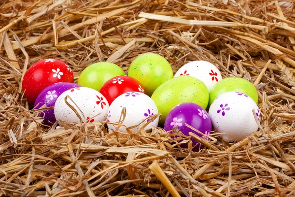 Coloridos huevos de Pascua pintados escondidos en un nido de paja —  Fotos de Stock