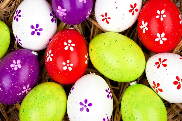 Coloridos huevos de Pascua pintados escondidos en un nido de paja —  Fotos de Stock