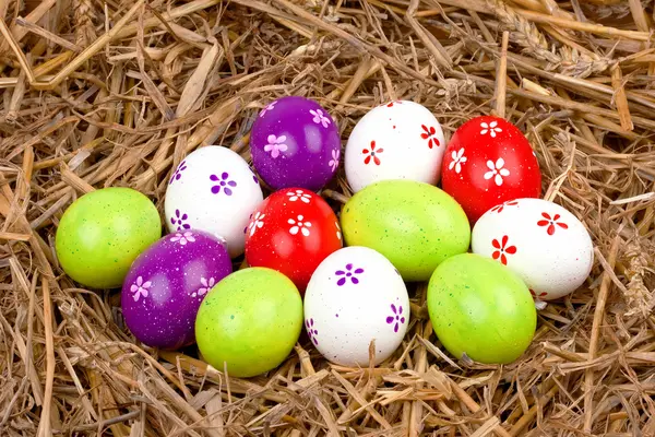 Barevné malovaná velikonoční vajíčka ukrytá v hnízdě ze slámy — Stock fotografie
