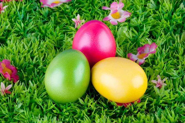 Barevné malování velikonočních vajíček, nachází se na louce s květinami — Stock fotografie