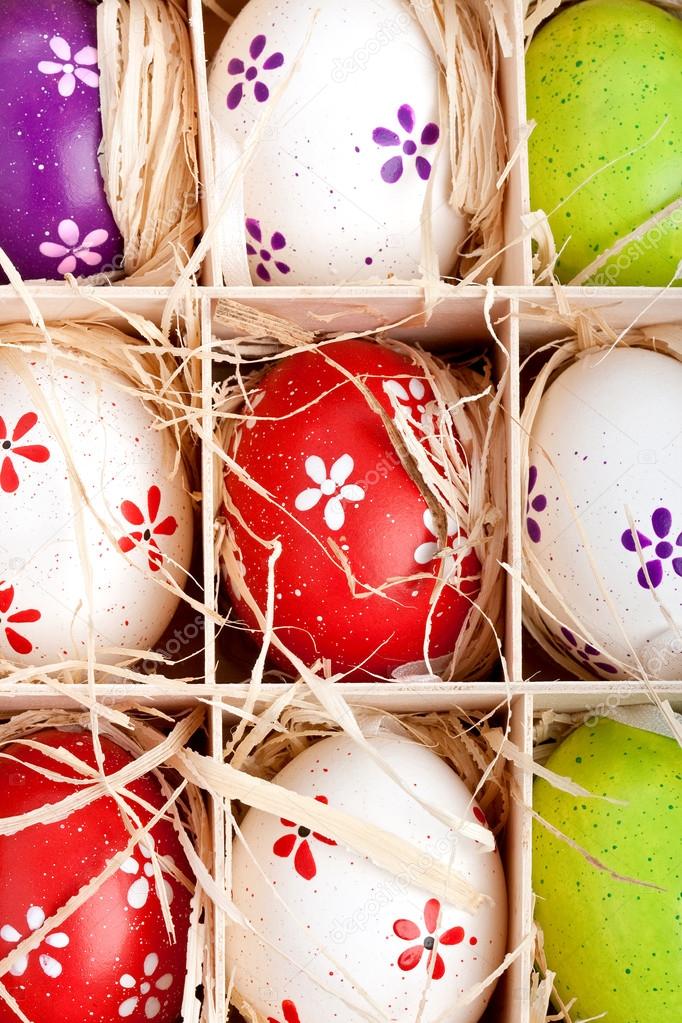 Assorted colorful painted easter eggs in a wooden box
