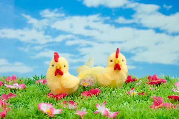 Coniglietto di Pasqua fatto di cioccolato con uovo di Pasqua su un prato verde con fiori davanti a un cielo blu — Foto Stock